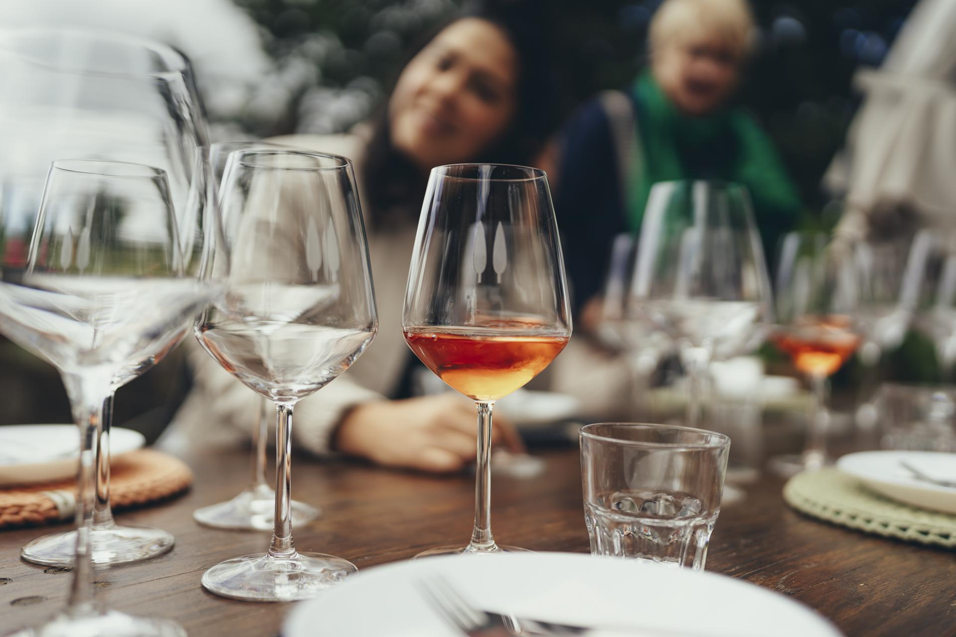 Wine glasses on a wooden table during a tasting in Chianti, one filled with amber wine