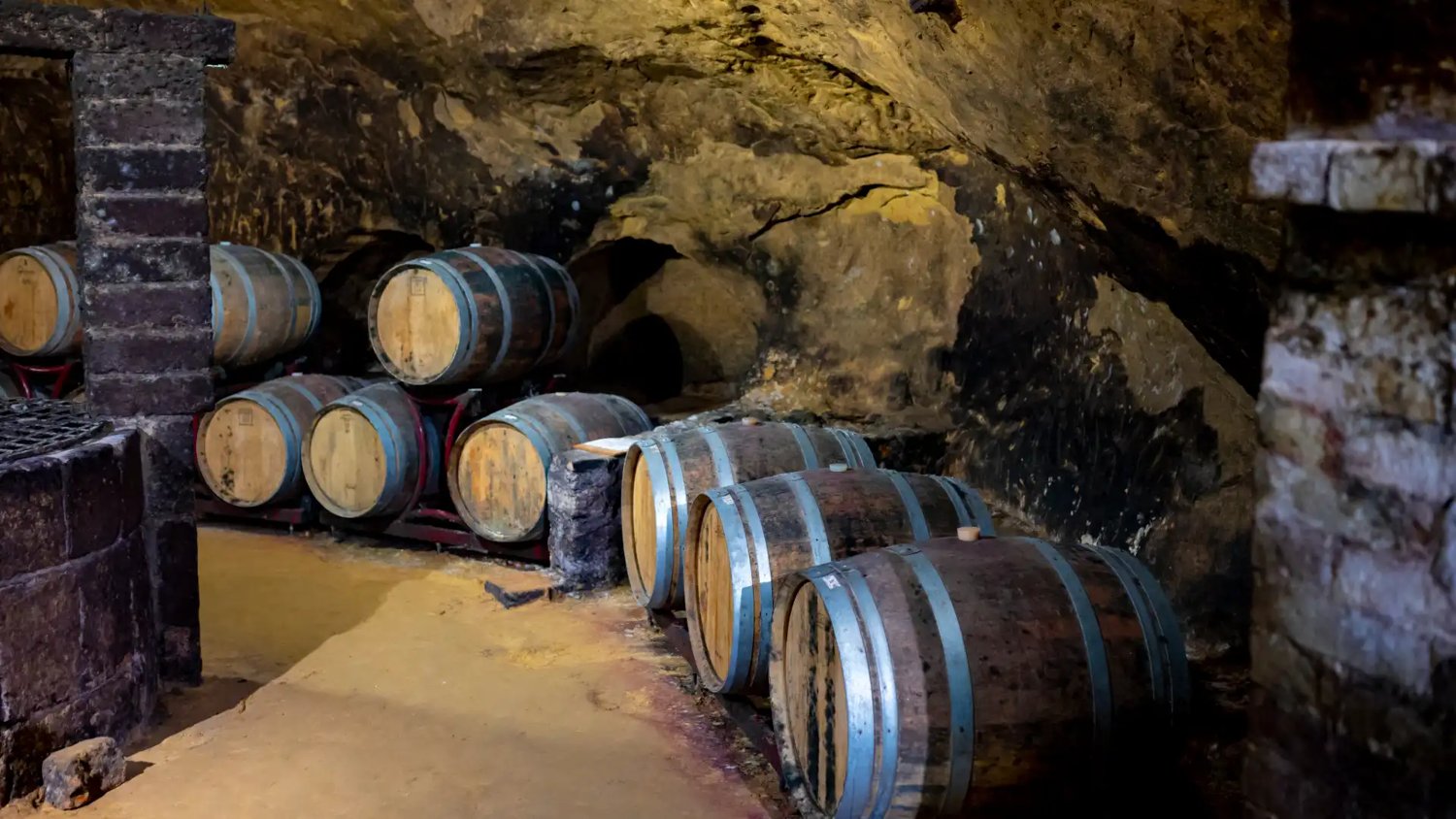 Oak barrels in an underground stone cellar, like those beneath Montepulciano where Vino Nobile ages