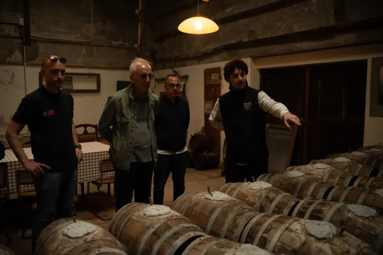 Guests visiting a vin santo cellar with small barrels in Tuscany