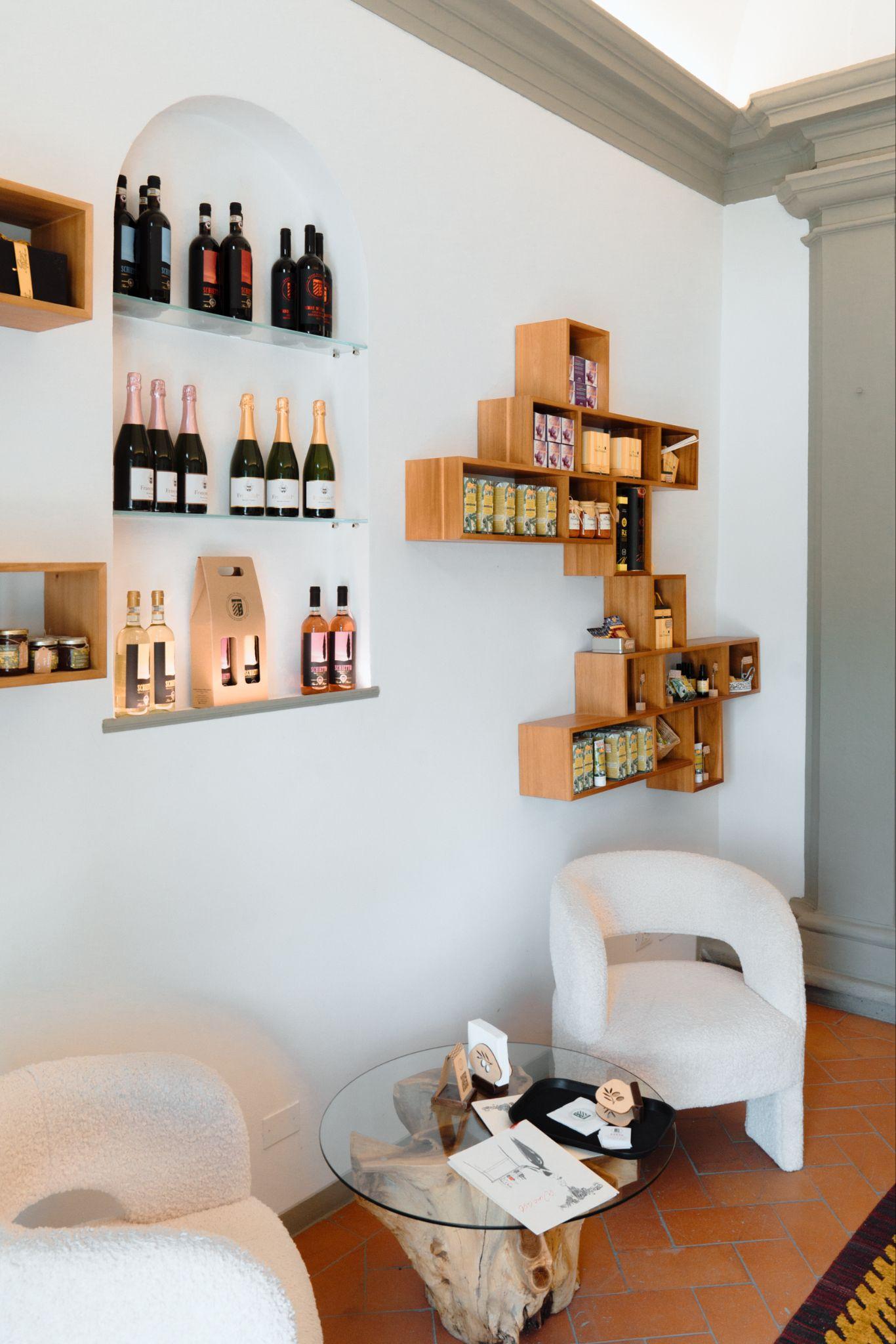 Bottles of red, white, rosé and sparkling wine in an arched wall niche beside wooden shelves of local products