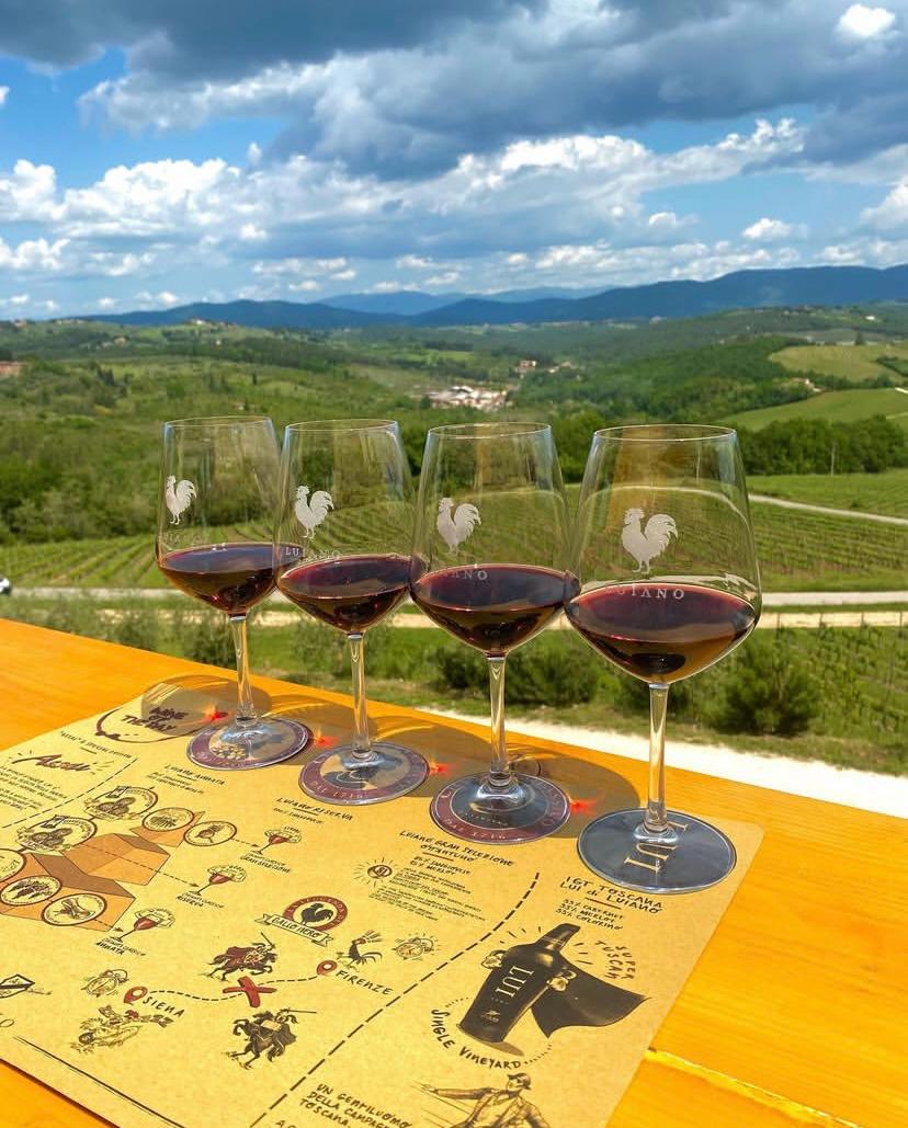 Four glasses of red wine on a tasting map, overlooking vineyards and hills in Chianti