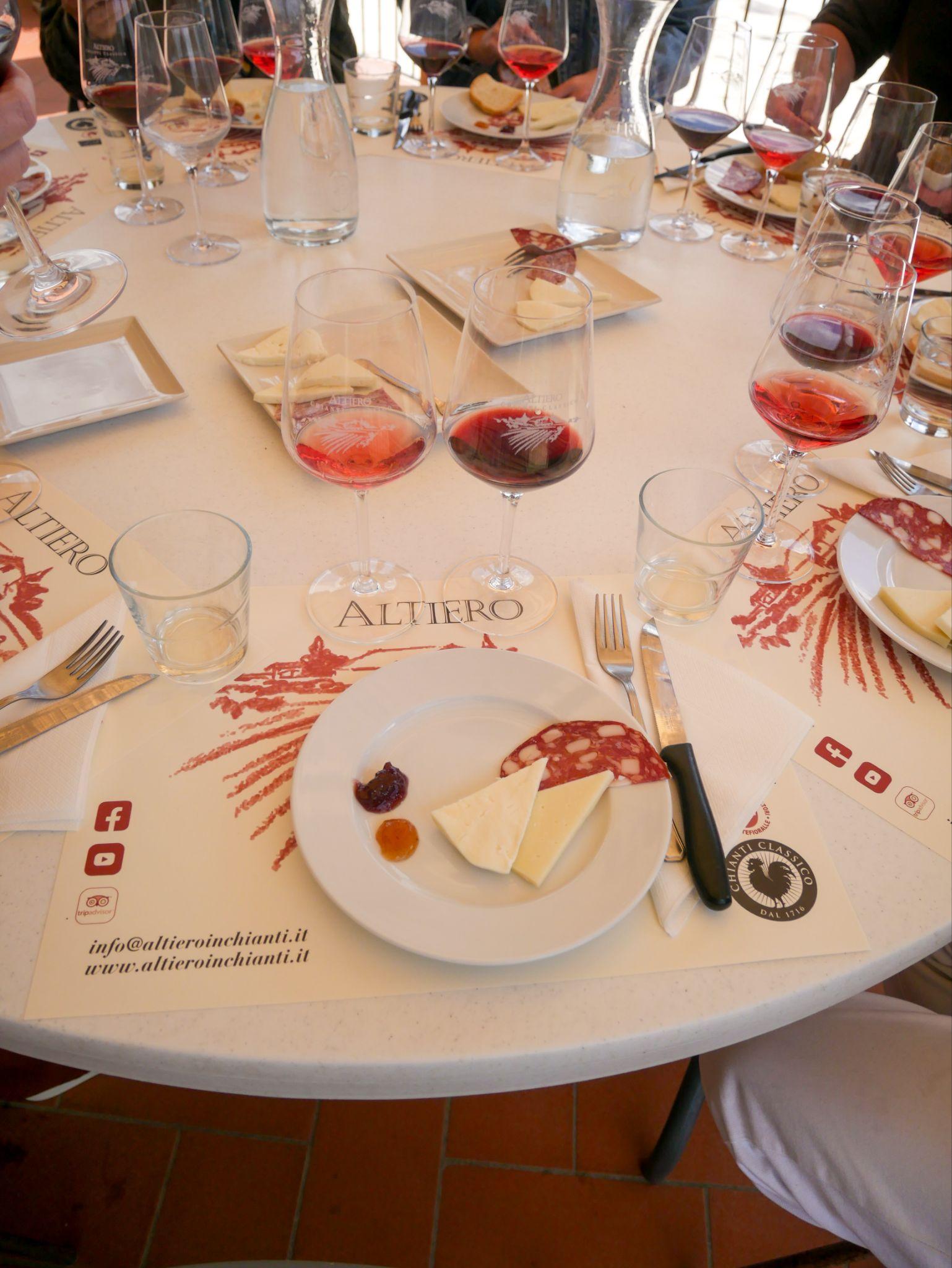 Glasses of red and rosé wine with cheese and salami on a tasting table at a Chianti winery